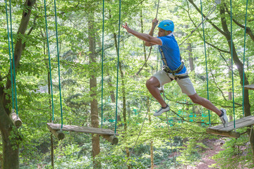 Man jumping while climbing in high rope course