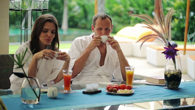 Couple talking during morning coffee by table in luxury villa
