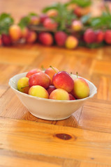 Plate of plums stands on wooden floor on blurred background