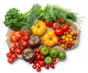 Composition of different varieties of tomatoes and herbs on a bu