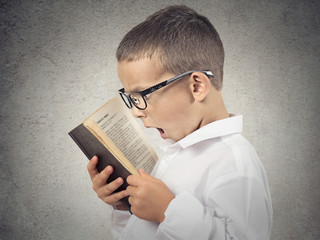 Side profile portrait surprised boy. Little man reading book