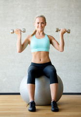 Fototapeta na wymiar smiling woman with dumbbells and exercise ball