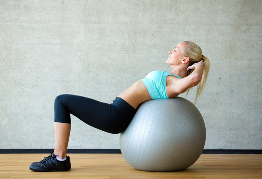 smiling woman with exercise ball in gym