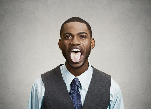 Man sticking his tongue out isolated grey wall background 