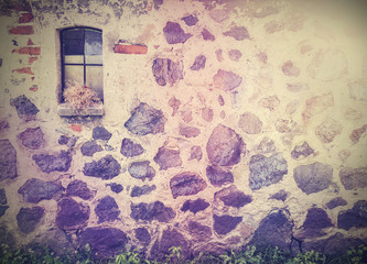 Vintage retro picture of stone wall with window.