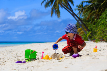 little boy playing with sand on the beach