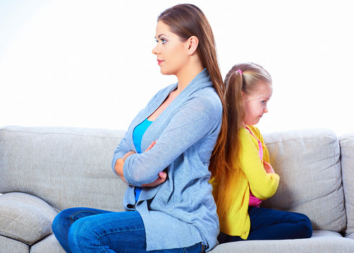 Woman with girl seating on sofa back to back.