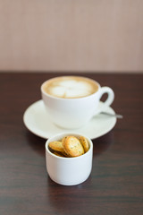 Cup of coffee and biscuits on wooden board