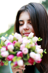 Fototapeta premium Portrait of a young beautiful woman smelling flowers
