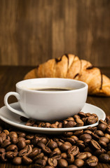 cup of coffee with coffee beans and croissant