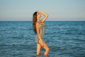 Young girl near the sea on a sunset