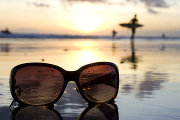 Sonnenbrille am Strand bei Sonnenuntergang mit Surfer