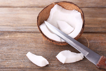 Broken coconut with knife on wooden background