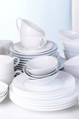 Set of white dishes on table on light background