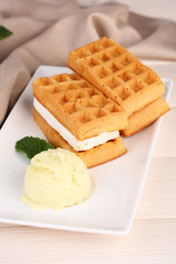 Tasty belgian waffles with ice cream on wooden table