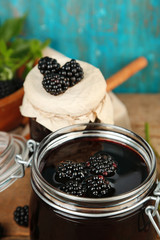 Tasty blackberry jam and fresh berries, on wooden table