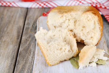Fresh baked bread on cutting board, on wooden background