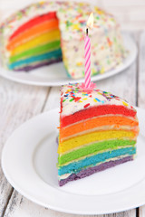 Delicious rainbow cake on plate on table on light background