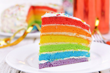 Delicious rainbow cake on plate on table close-up