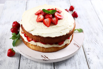Delicious biscuit cake with strawberries on table close-up