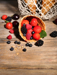Different ripe berries in sugar cones, on wooden background