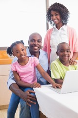 Cute siblings using laptop together with parents