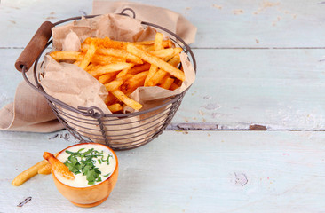 Tasty french fries in metal basket on wooden table