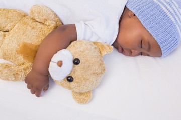 Adorable baby boy sleeping peacefully with teddy