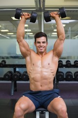 Fototapeta na wymiar Muscular man exercising with dumbbells in gym