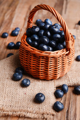 Delicious blueberries in wicker basket on table close-up