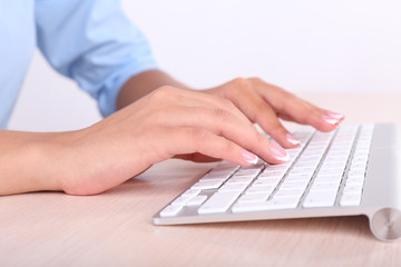 Fototapeta na wymiar Female hands typing on keyboard, close-up, on light background