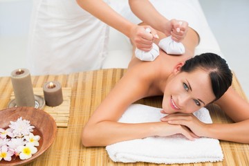 Obraz na płótnie Canvas Brunette enjoying a herbal compress massage