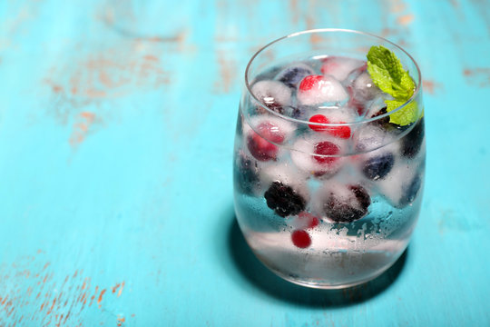 Cold cocktail with forest berries, frozen in ice cubes