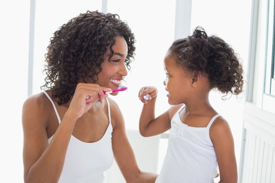 Pretty mother with her daughter brushing their teeth