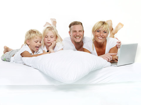 Happy family with laptop stay in bed