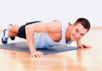 Fototapeta na wymiar smiling man doing push-ups in the gym