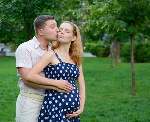young couple awaiting baby posing outdoor in summer park, husban
