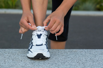 Closeup of female hands tying running shoes laces