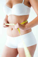 Young woman measuring her waist by measure tape.