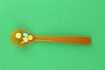 Plastic spoons with color pills on green background
