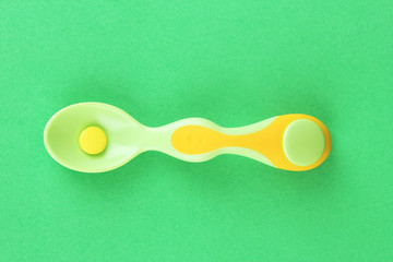 Plastic spoons with color pills on green background
