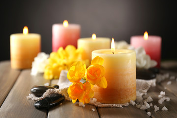Beautiful candles with flowers on wooden background