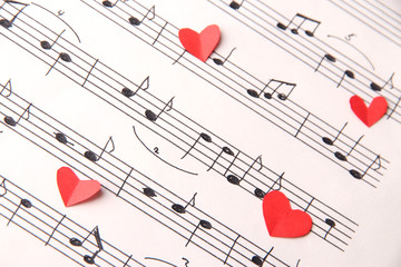 Red paper hearts on music book, close-up