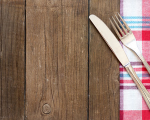 Fork and knife on kitchen towel and old wooden table