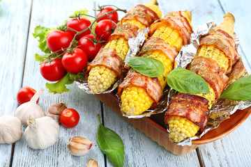 Grilled bacon wrapped corn on table, close-up