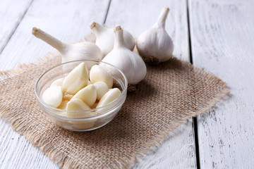 Fresh sliced garlic in glass bowl on wooden background