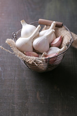 Garlic in basket on black wooden background