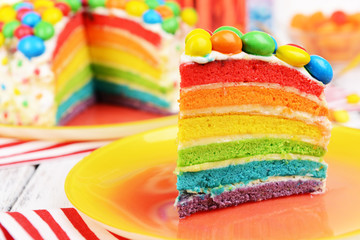 Delicious rainbow cake on plate on table close-up
