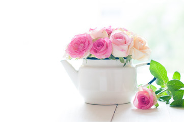 roses in a white enameled vintage teapot