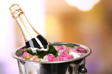 Frozen rose flowers in ice cubes and champagne bottle in